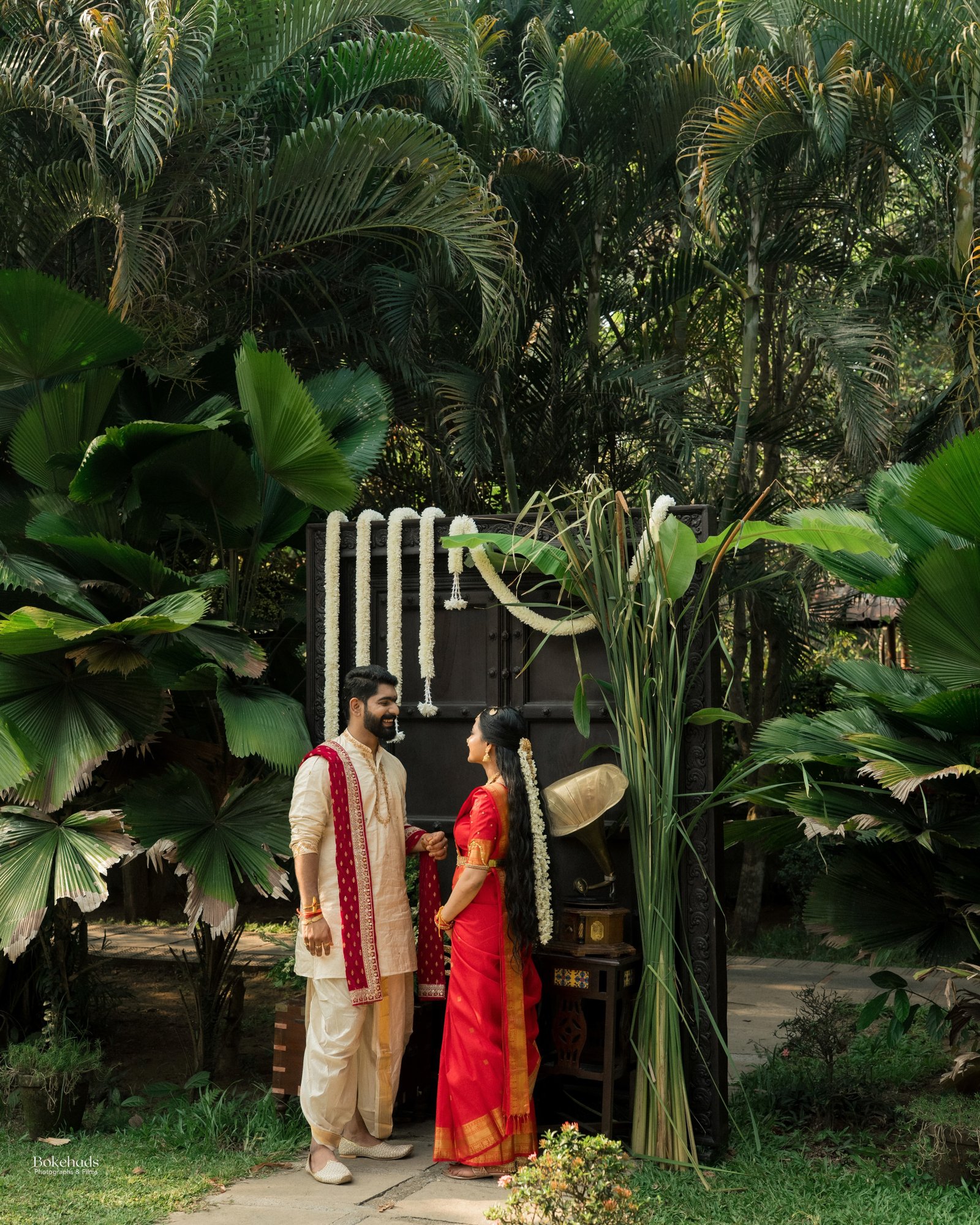 A couple in traditional attire standing together in a lush garden