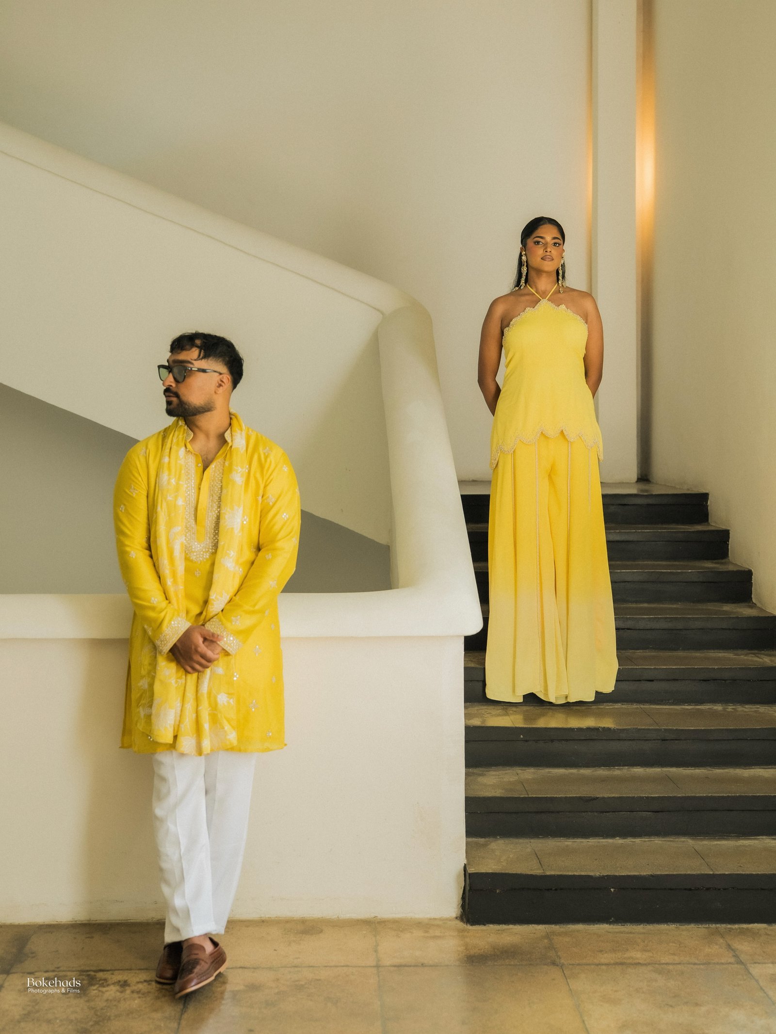 A couple posing on a sculptural staircase in coordinated yellow attire