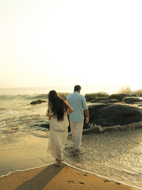 A couple walking together along the shore at sunset