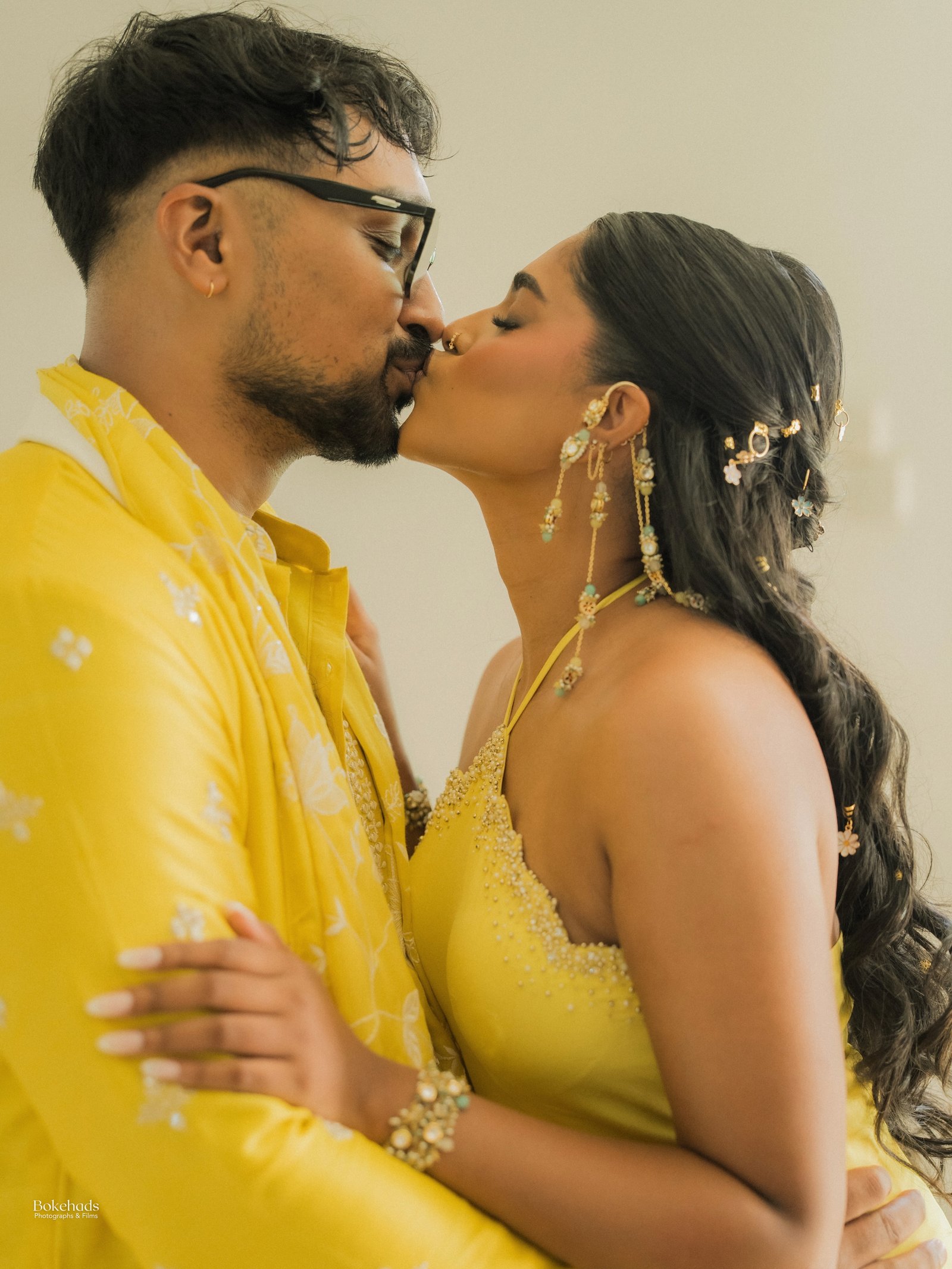 A couple in coordinated yellow attire sharing a kiss